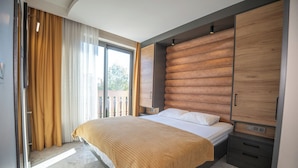 A modern bedroom with a large bed, wooden headboard, and a sliding door closet. - Kalender Pansiyon Fethiye (Fethiye)