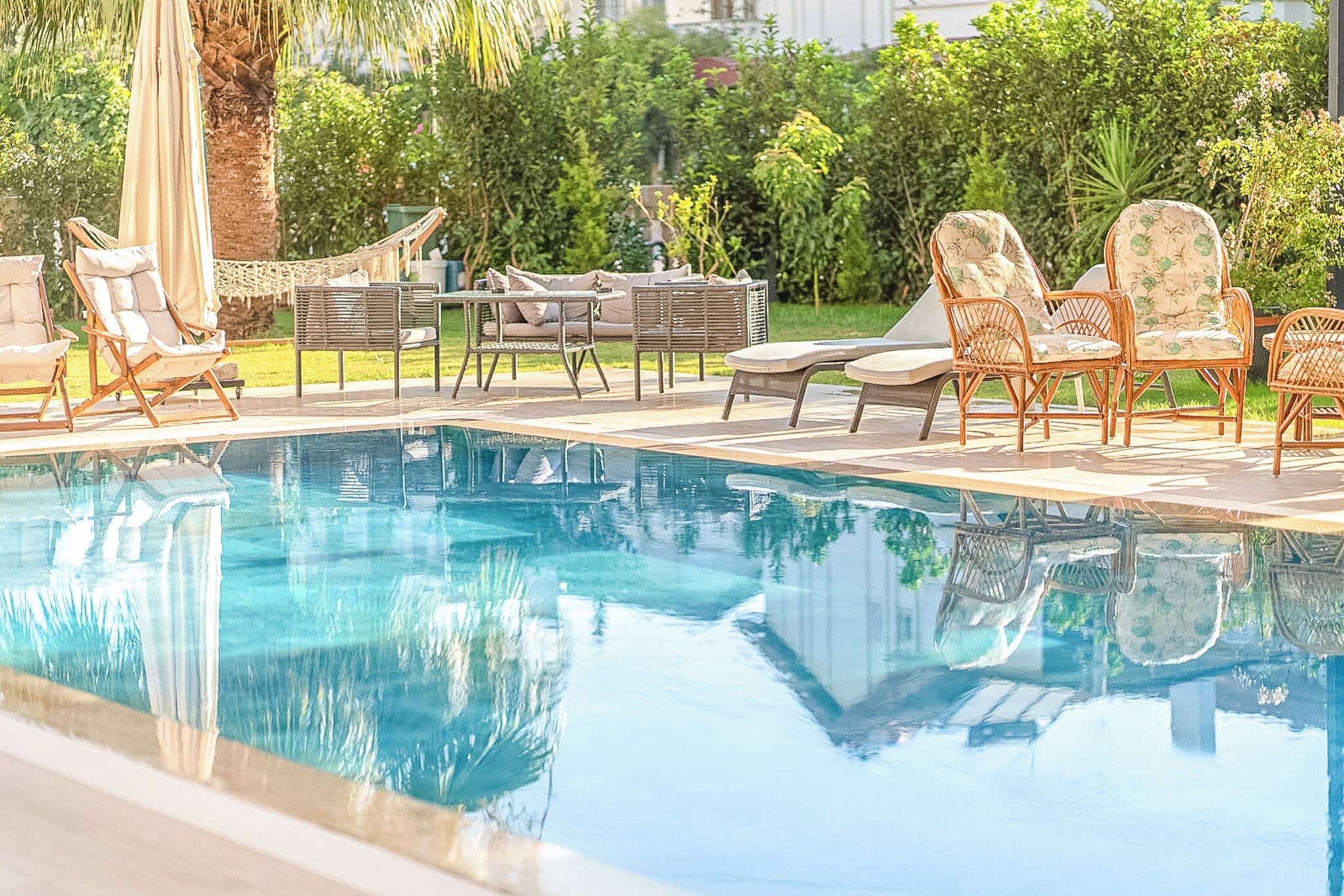 Una piscina al aire libre, sombrillas, sillones reclinables de piscina