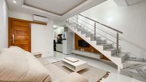 Una sala de estar moderna con un sofá, una mesa de centro y una escalera con detalles de mármol.