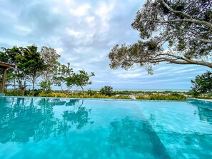 Una piscina cristallina con vista sul mare e sulla vegetazione circostante.