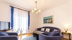 Un salon avec un canapé, une table basse, un téléviseur et un tableau accroché au mur.