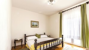 Une chambre à coucher avec un lit en bois, une table de chevet, un tapis et une fenêtre avec des rideaux.