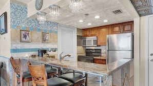 A kitchen with a marble countertop, stainless steel appliances, wooden cabinets, and a decorative backsplash. - Wake to Waves at Long Beach Resort, Oceanfront Views W/Free Beach Chair Service (Panama City Beach)