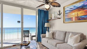 A balcony with a view of the ocean, a sofa, a table with remote controls, and a painting on the wall. - Wake to Waves at Long Beach Resort, Oceanfront Views W/Free Beach Chair Service (Panama City Beach)