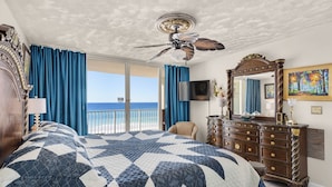 A bedroom with a large bed, a ceiling fan, a dresser, a TV, and a view of the ocean. - Wake to Waves at Long Beach Resort, Oceanfront Views W/Free Beach Chair Service (Panama City Beach)