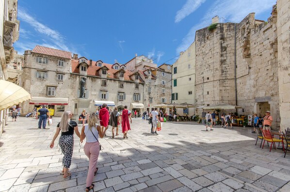 A historic square with stone buildings, outdoor seating, and people walking. - Apartment Toni Delux (Split)