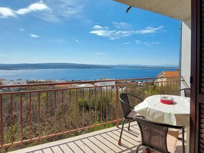 A balcony with a table and chairs, overlooking a body of water and distant hills. - Apartments Dara (Crikvenica)