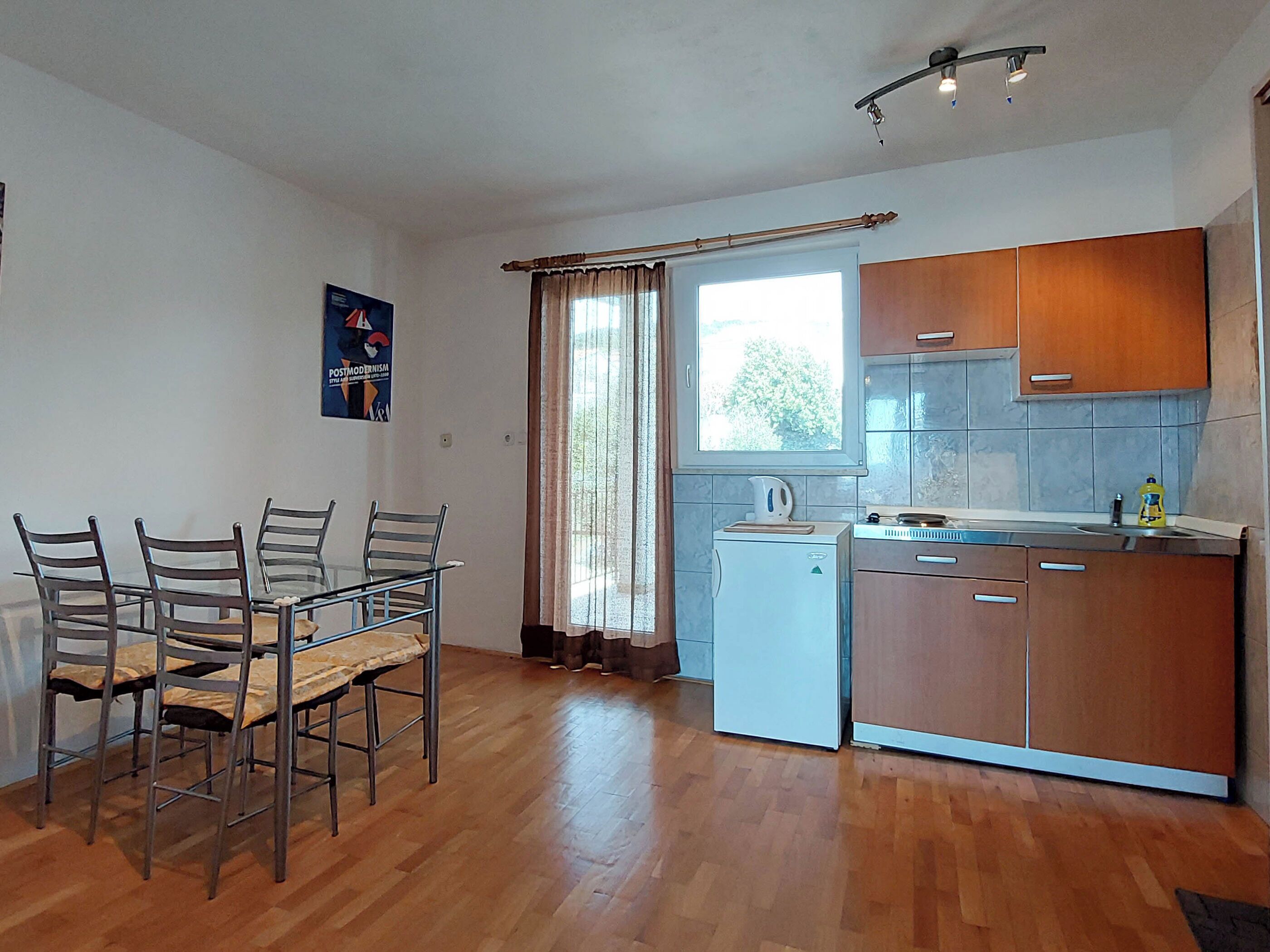 Una cocina compacta con armarios de madera, lavavajillas integrado y un comedor con mesa y sillas.