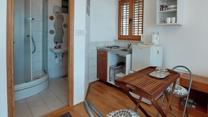 Eine kleine Küche mit Spüle, Kühlschrank und einem Fenster mit Jalousien.