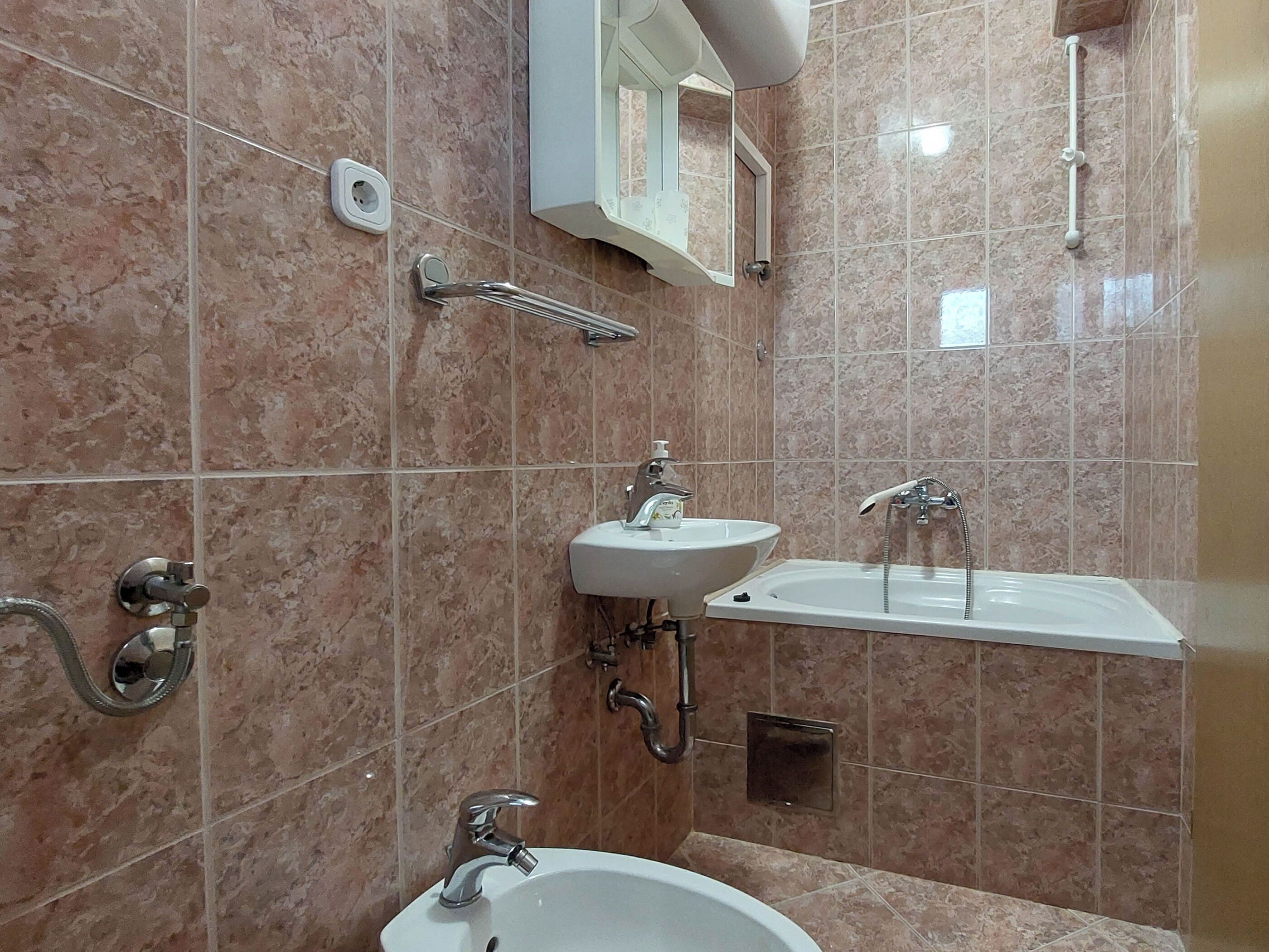 A bathroom with a sink, mirror, and shower.