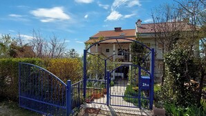 Ein begrenzter Zugang zu einem Wohnanwesen mit rotem Ziegeldach und einem Balkon.