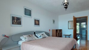 Ein Schlafzimmer mit Bett, einer Bank, einem Holzkasten und einem Spiegel.