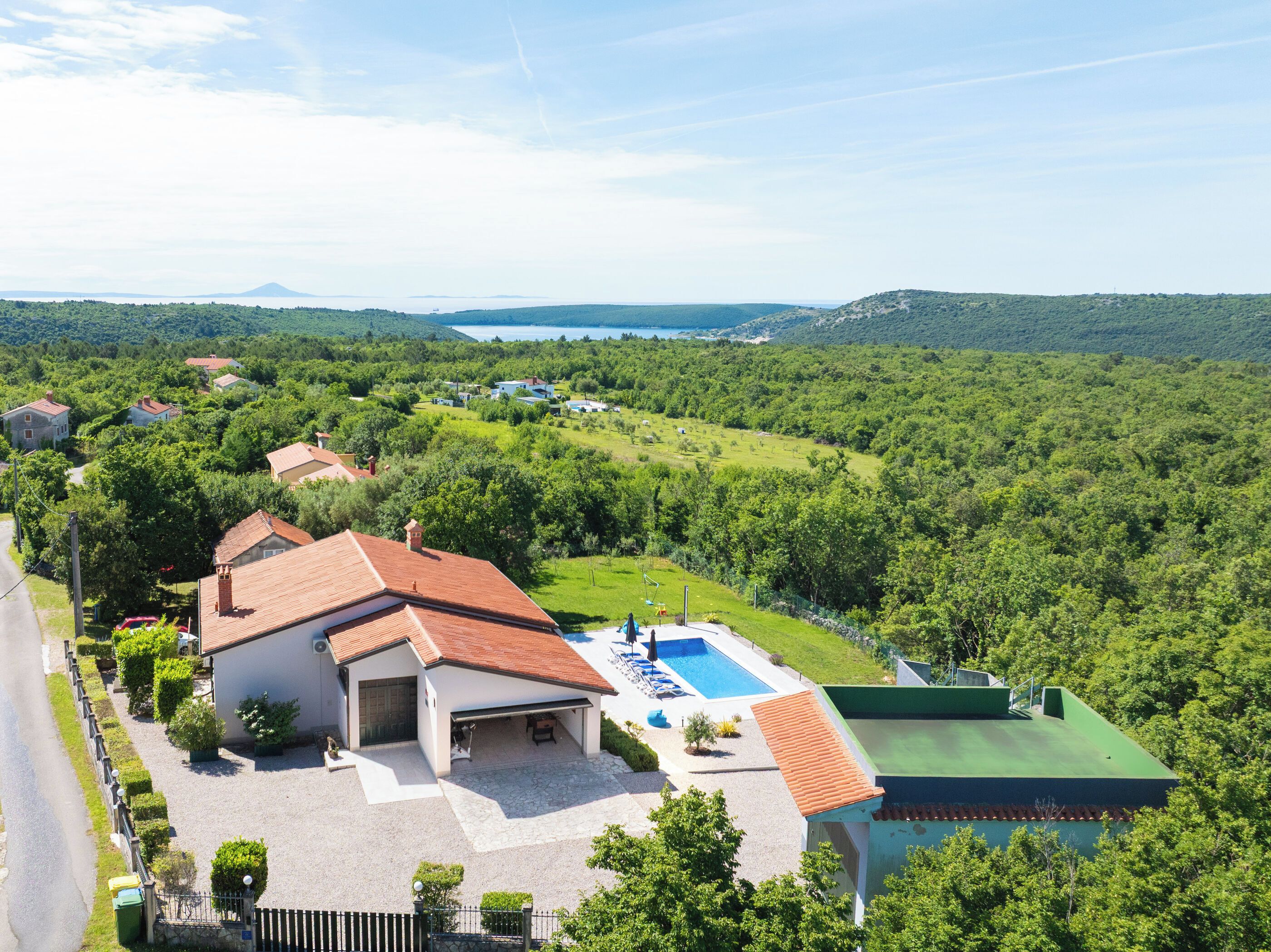 Zona residencial con piscina, casas y vistas a un lago y montañas.
