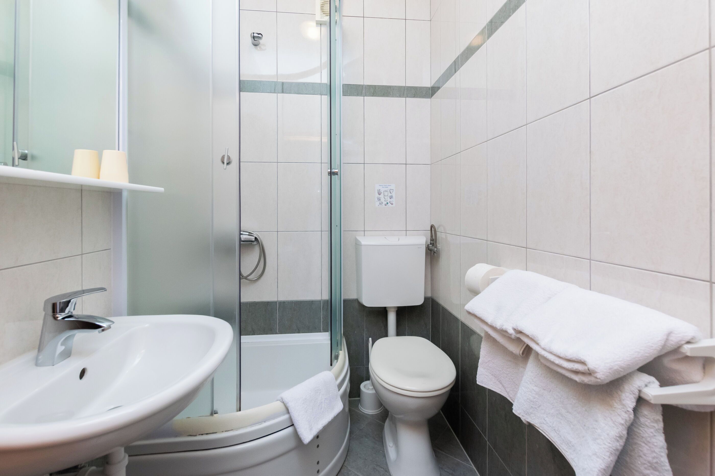 Een badkamer met een wastafel, toilet, douche en glazen deur.