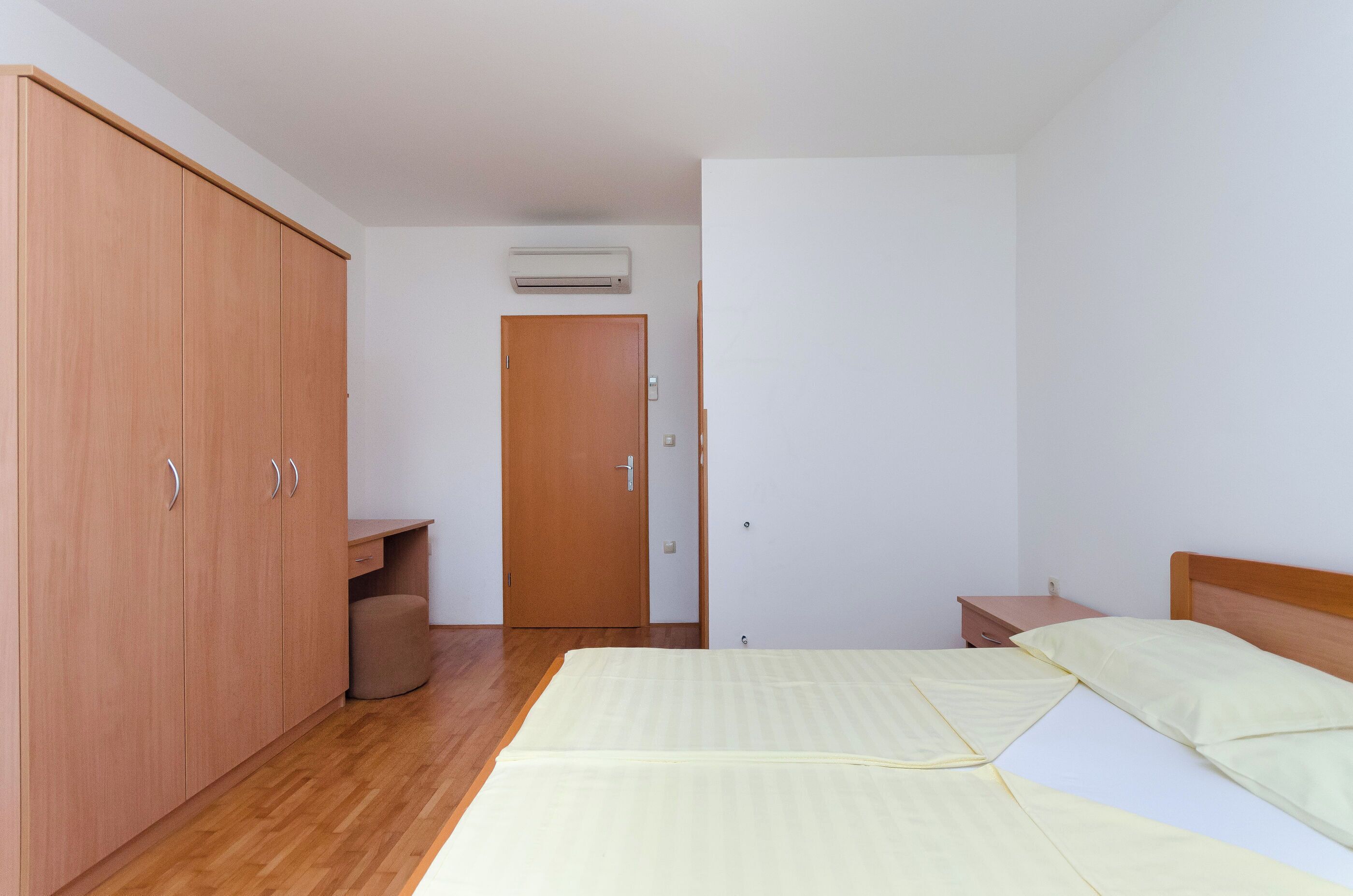 A bedroom with a bed, a wardrobe, a desk, and a door.