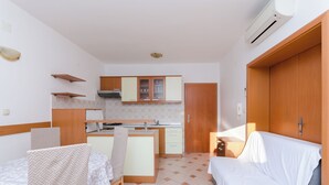 A compact kitchen with a dining area and a sofa. - Apartments Josip S (Lopar)