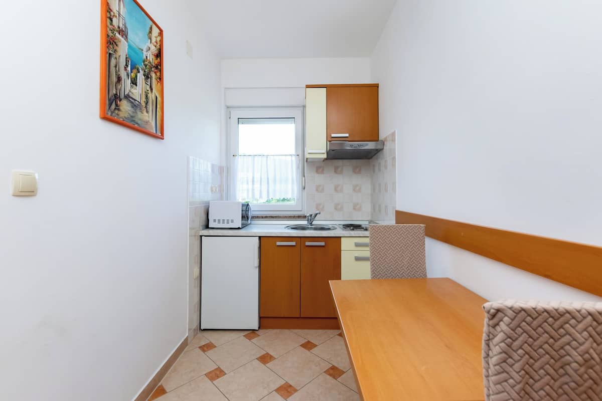 A compact kitchen with a refrigerator, stove, and wooden cabinets.