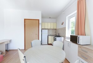 A compact kitchen with a dining area, a refrigerator, a microwave, and a window with curtains. - Apartment Neda M (Lopar)