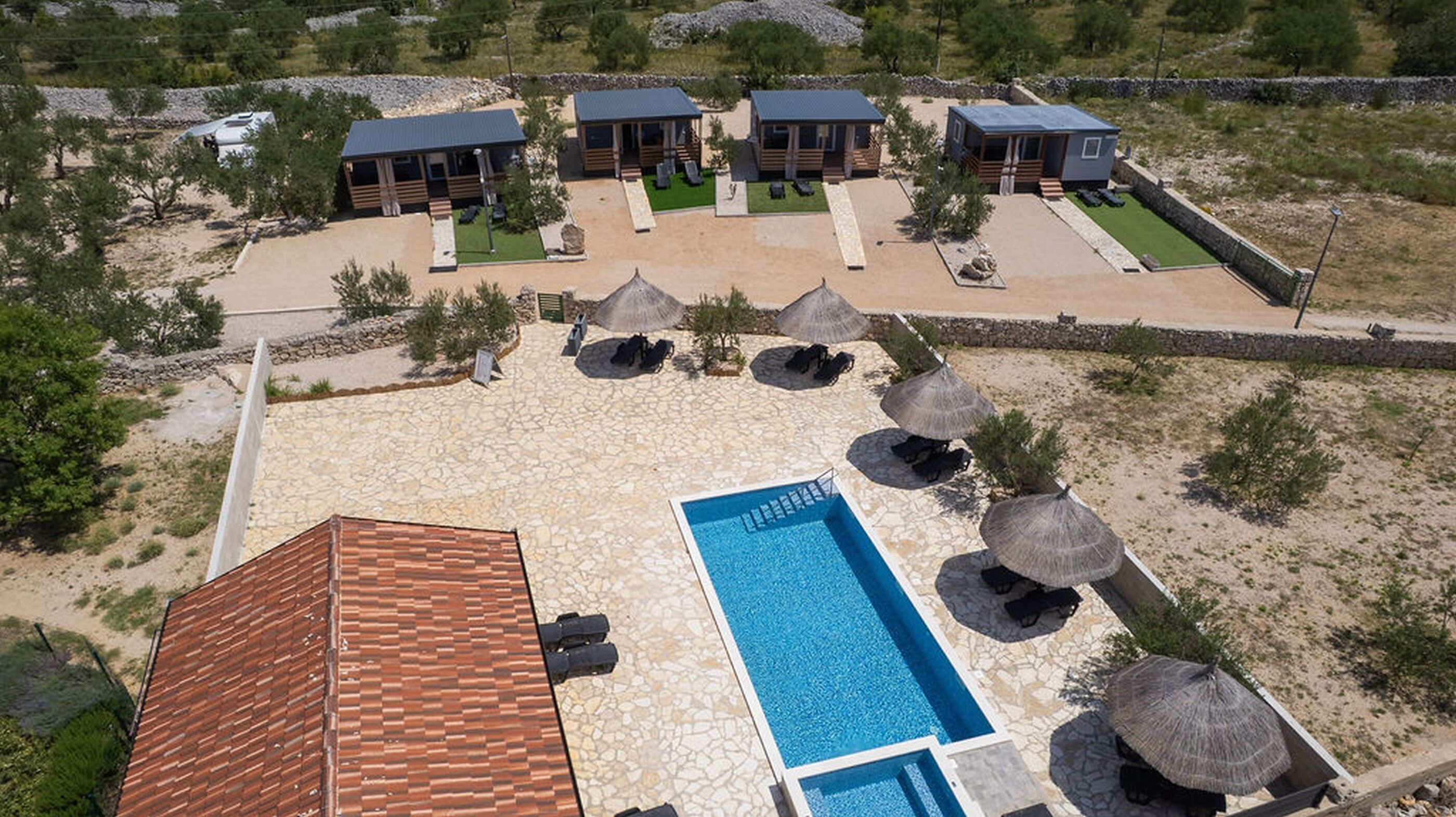 A resort with a swimming pool, multiple cabins, and outdoor seating areas.