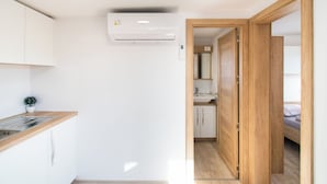 A compact kitchen with white cabinets, a wooden countertop, and an air conditioning unit. - Mobile Home Banovi Dvori (Tisno)