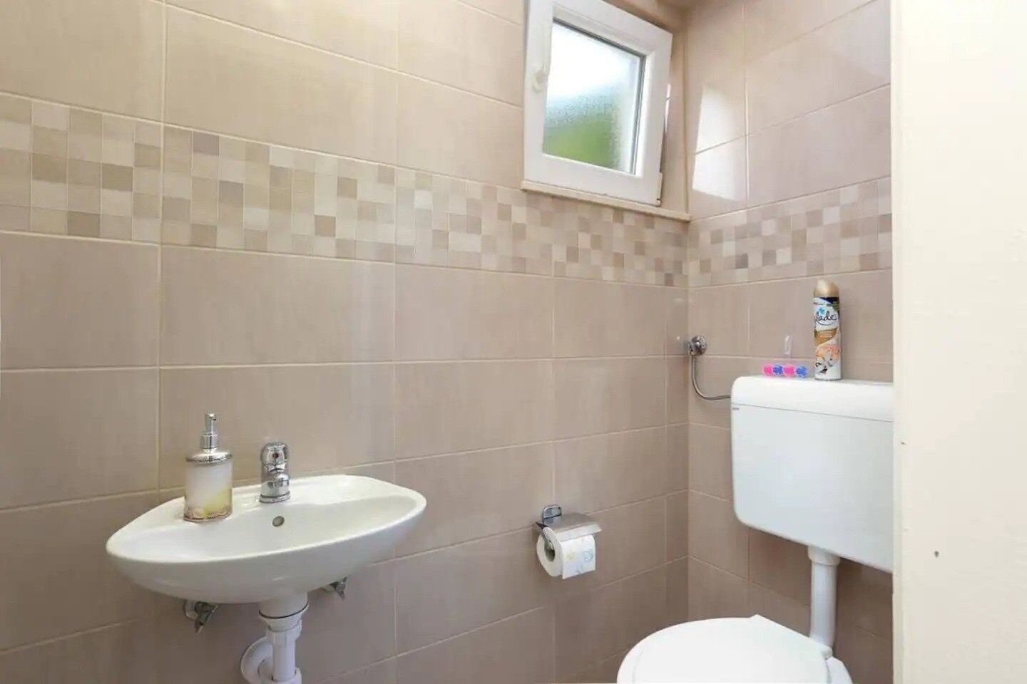 A bathroom with a sink, toilet, and a window.