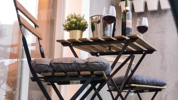 A dining area with a table set for two, featuring a potted plant, wine glasses, and a bottle. - House Neda (Marina)