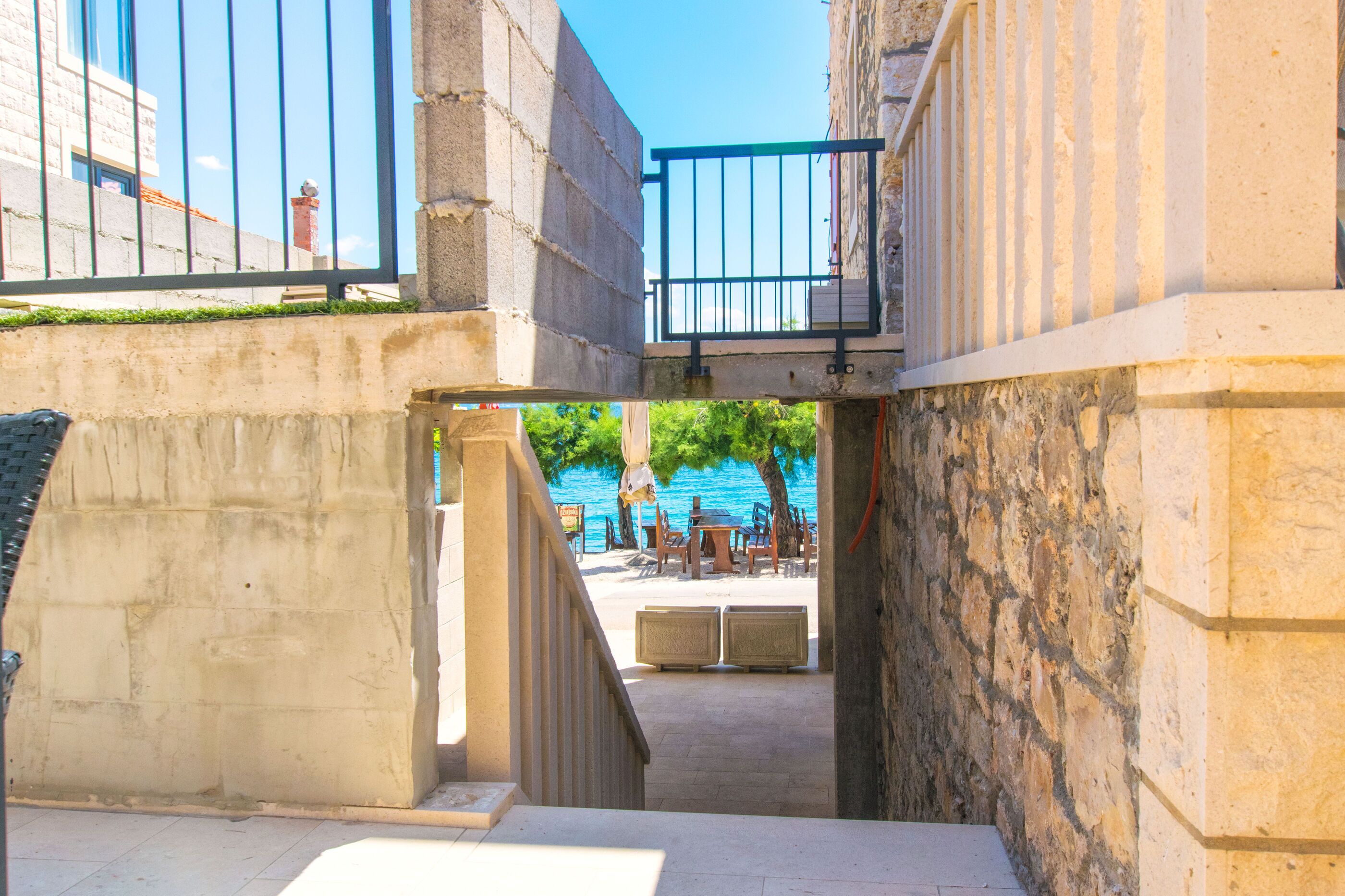 A stone staircase leading to a terrace with outdoor seating and a view of the sea.