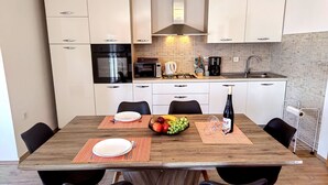 Una cocina moderna con armarios blancos, una campana extractora de acero inoxidable, un microondas y un fregadero.