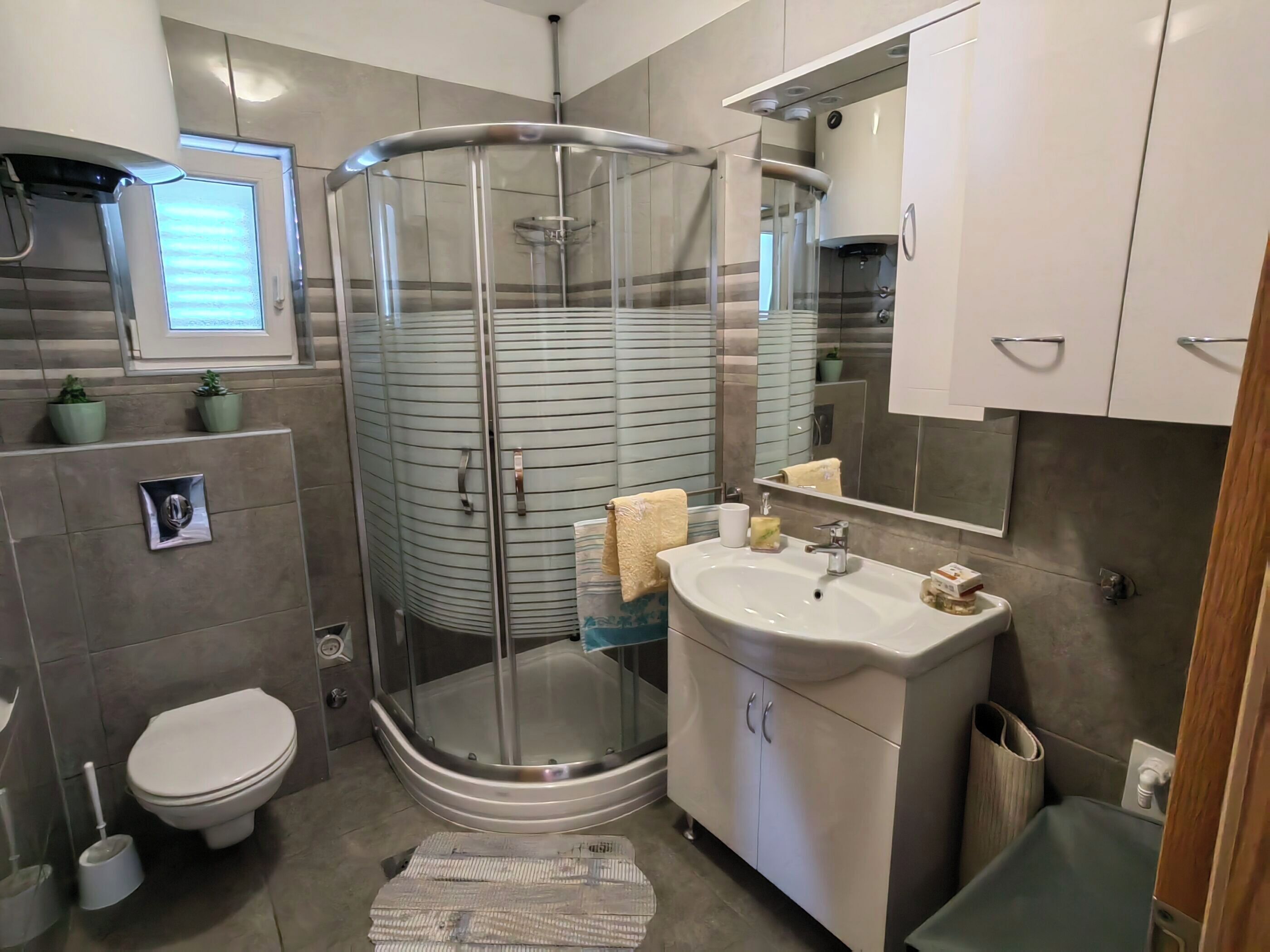 Ein modernes Badezimmer mit einer Duschkabine, einer Toilette und einem Waschbecken mit Spiegel.