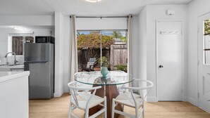 Eine moderne Küche mit Kühlschrank, Mikrowelle und Essbereich mit Glastisch und weißen Stühlen.