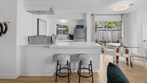 Eine moderne Küche mit einer zentralen Kochinsel, Barhocker und einem Essbereich mit Tisch und Stühlen.