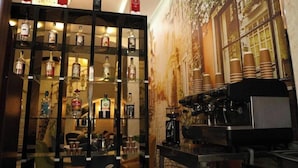 A bar area with shelves of liquor bottles, a coffee machine, and a mural of a building. - Dionis Hotel (Baku)