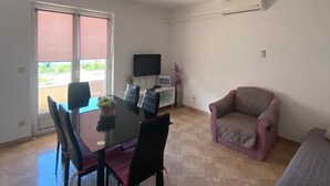 Een eethoek met een tafel, stoelen, een bank, een televisie en een airconditioning.