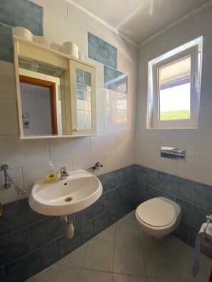 Une salle de bain équipée d’un lavabo, de toilettes et d’une fenêtre donnant sur l’extérieur.