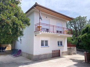 A two-story building with a balcony, a concrete patio, and a gate. - Apartment Niko (Novi Vinodolski)