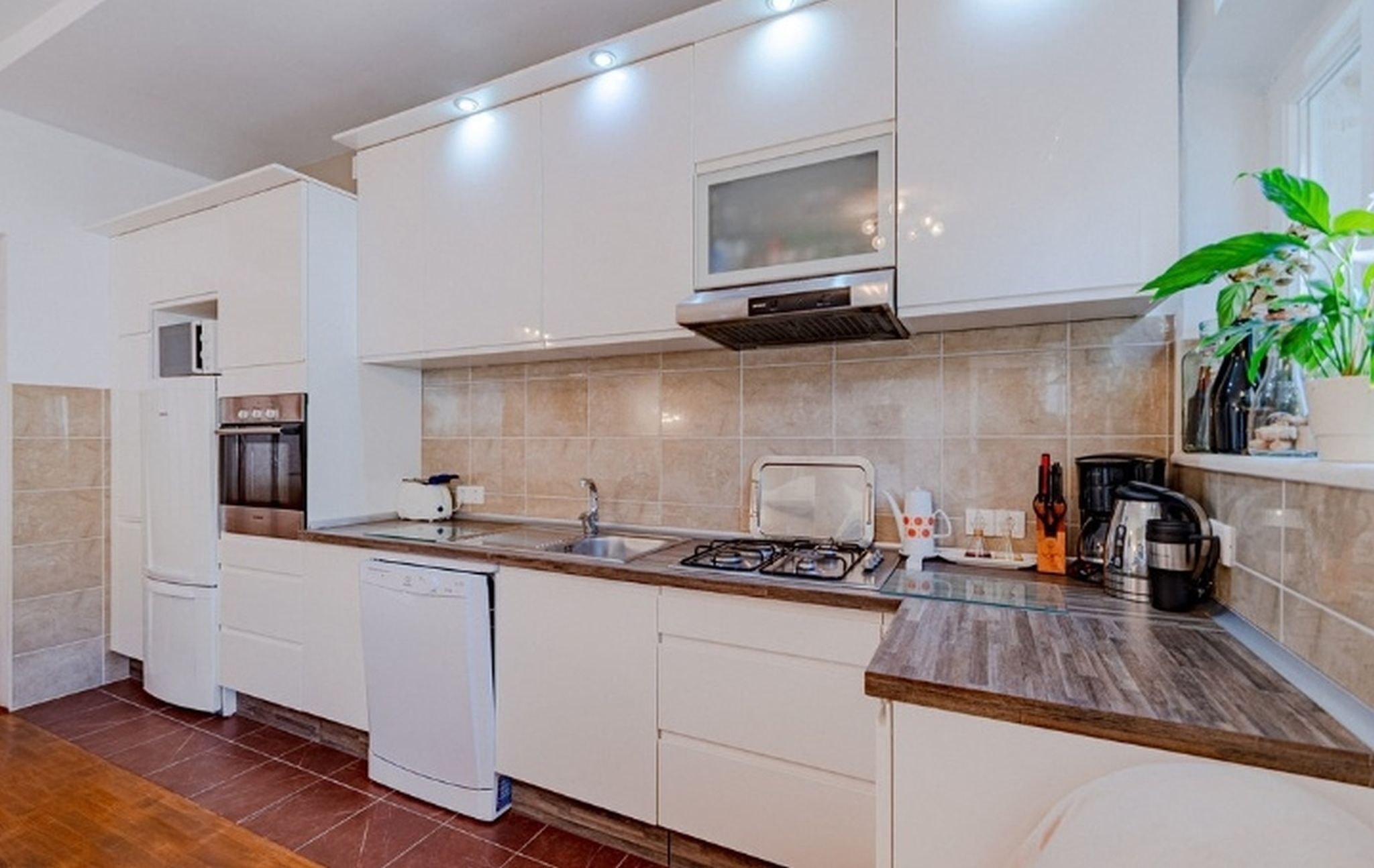A modern kitchen with white cabinets, a built-in microwave, a gas stove, and a dishwasher.