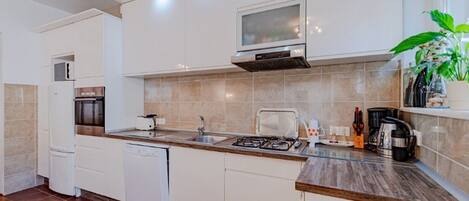 A modern kitchen with white cabinets, a built-in microwave, a gas stove, and a dishwasher.