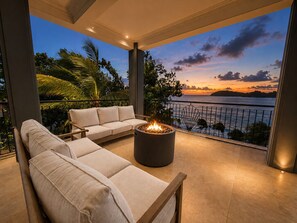 Un balcone con divano, un braciere e vista sull'oceano al tramonto.