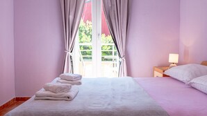 A bedroom with a bed, a nightstand, and a window with curtains. - Apartments Alex (Rasa)