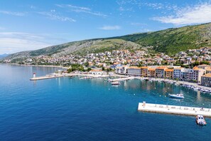 A coastal town with a marina, buildings with orange roofs, and a lighthouse. - Apartments Ante (Senj)