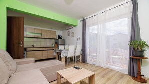 A modern living room with a sofa, a wooden coffee table, and a dining area with chairs and a table. - Apartments Ante (Senj)