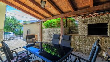 Un patio al aire libre con una mesa de vidrio, sillas y un muro de piedra.