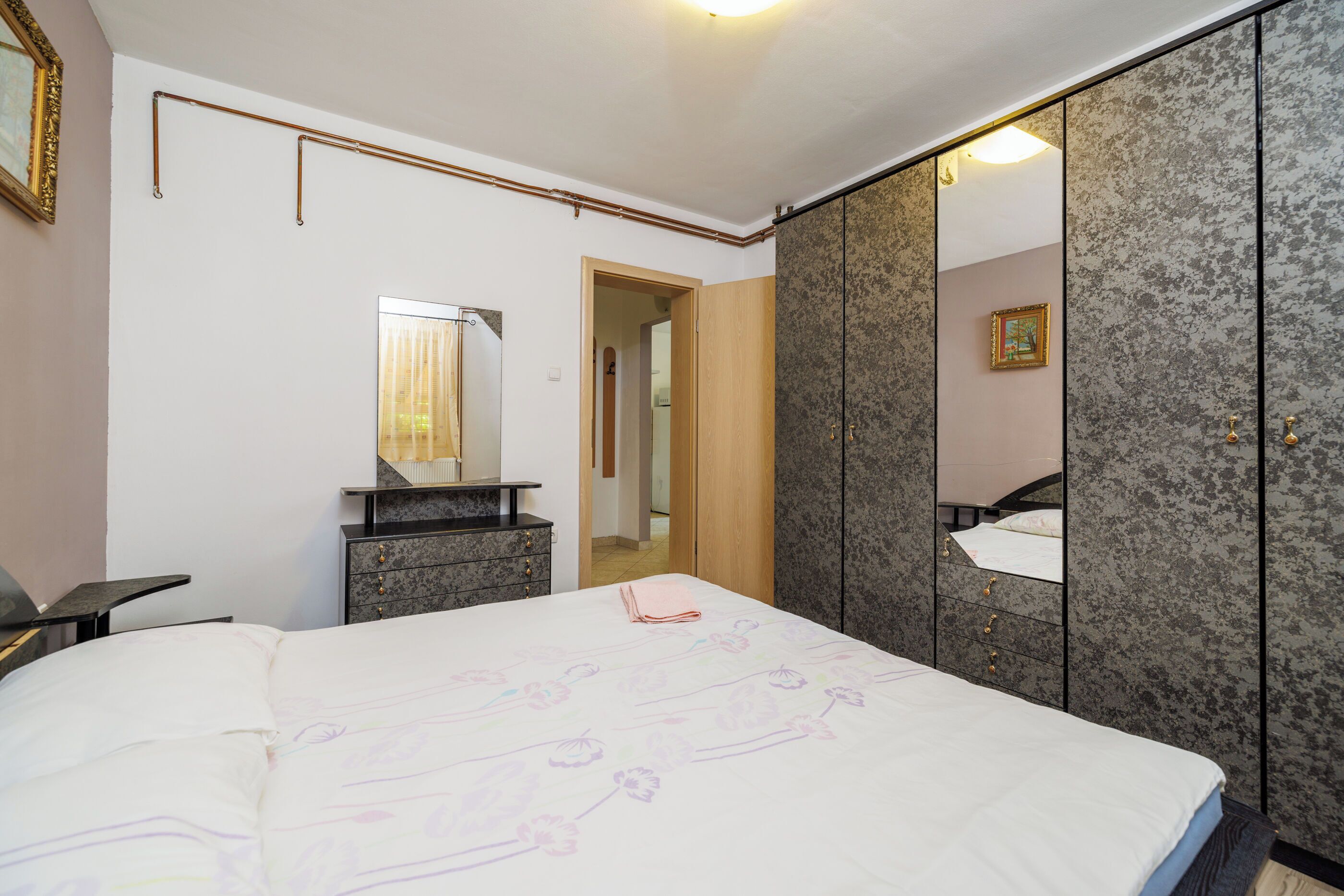 Un dormitorio con cama, cómoda, espejo y armario.