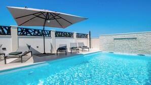 Un área de piscina con sillas de descanso y una sombrilla.