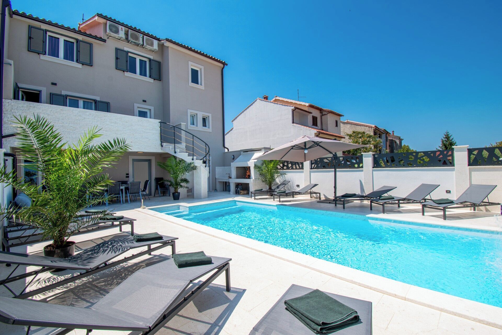 A swimming pool with lounge chairs and a staircase leading to an upper level.