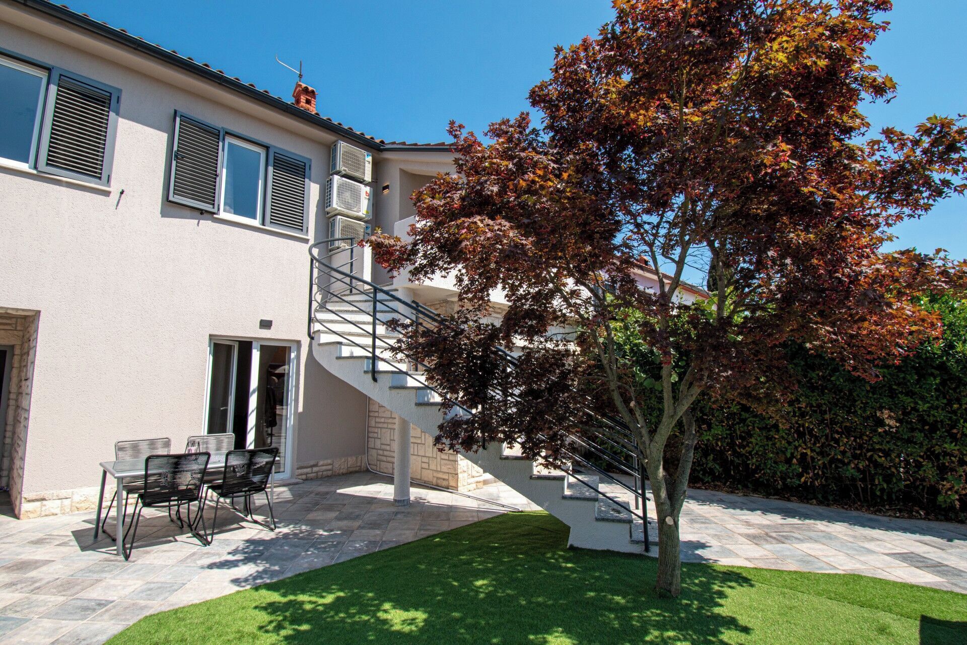 A two-story building with a staircase, outdoor seating, and a well-maintained lawn.