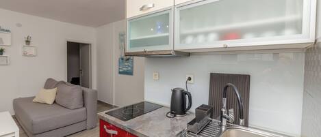 A compact kitchen with a built-in stove, a sink, and a coffee maker.