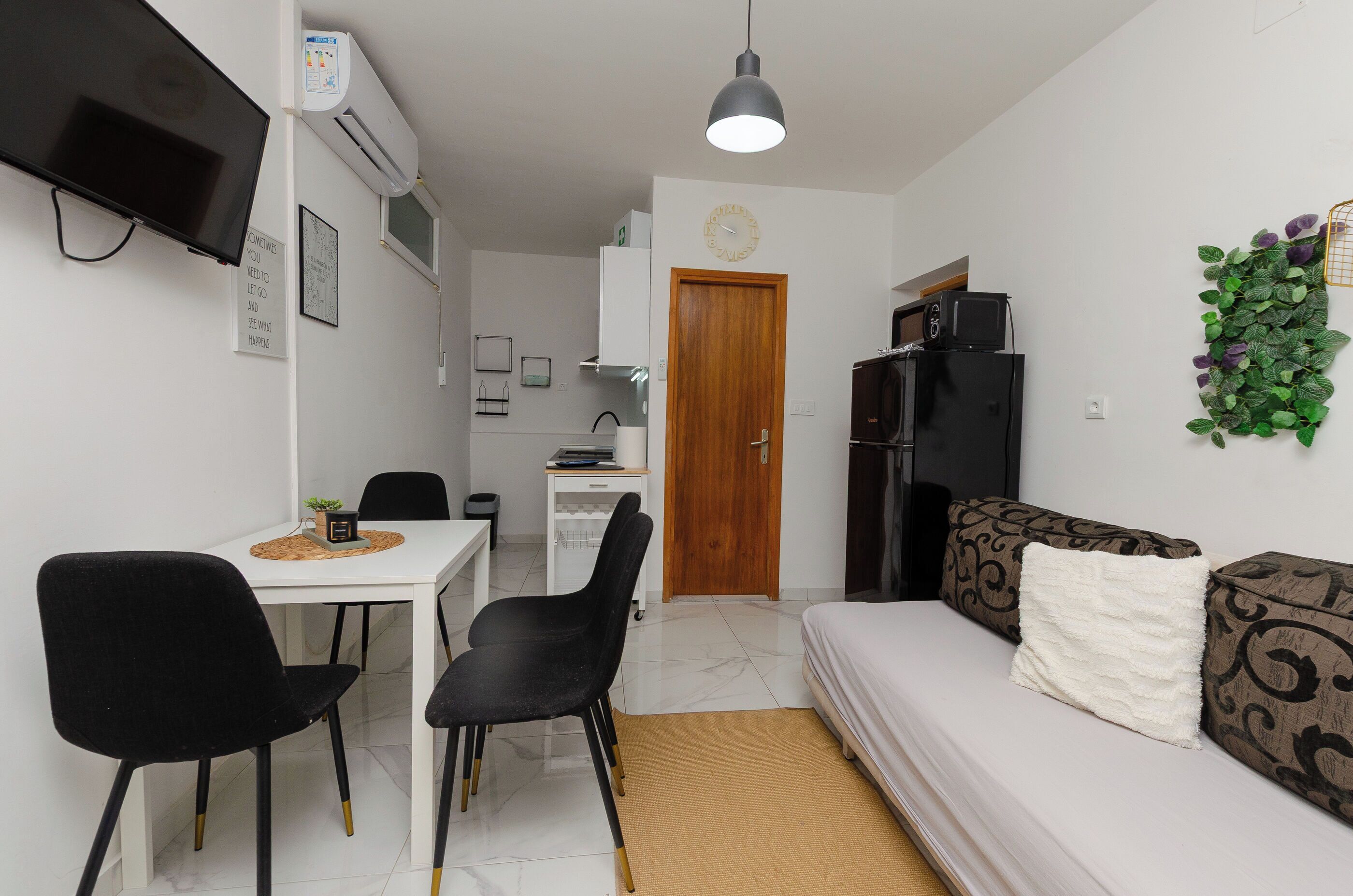 A compact living space with a TV, kitchenette, dining area, and a sofa.
