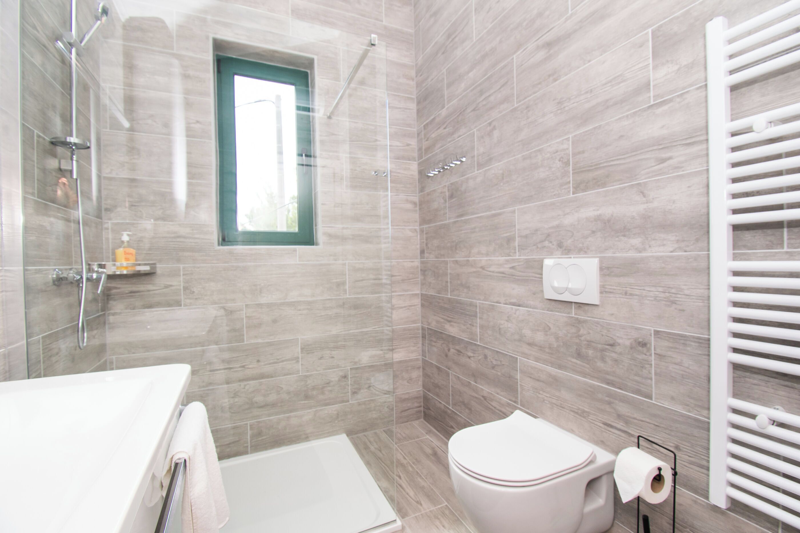 Et moderne badeværelse med bruser, toilet og badekar.