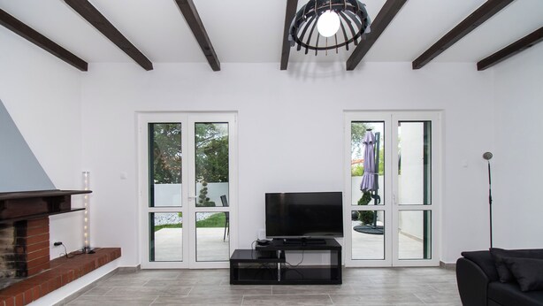 A modern living room with a fireplace, a flat-screen TV, and a black sofa. - Villa Mungo (Starigrad)